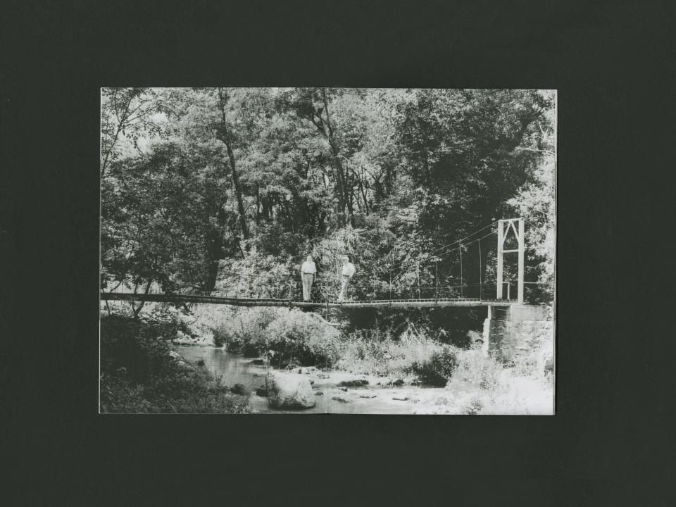 two men on a bridge above a river