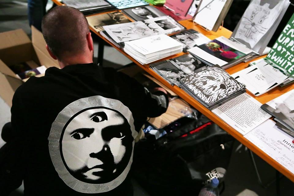 A guy from behind, sitting at his book stand