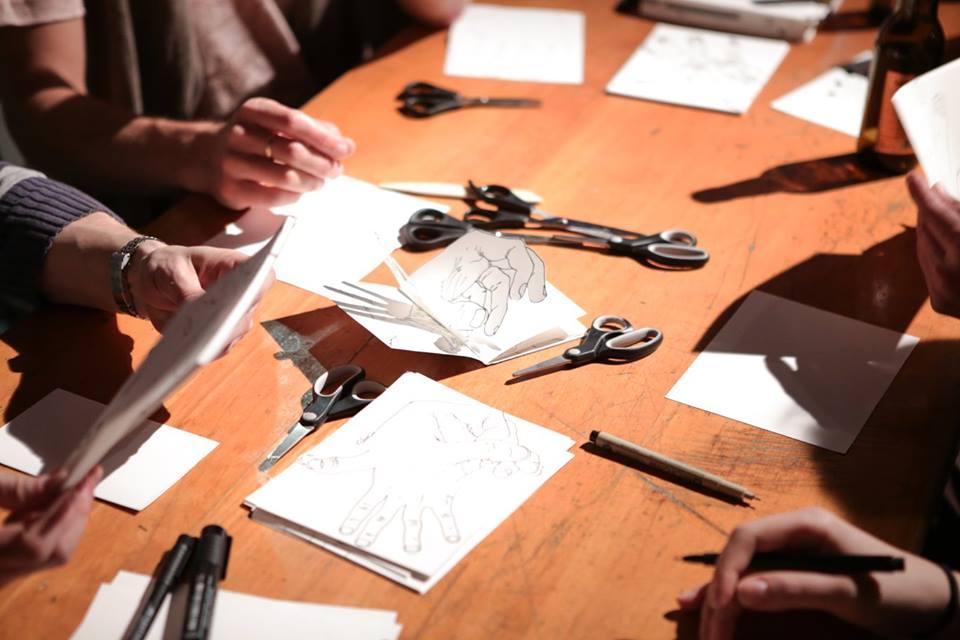 People sitting at a table making zines