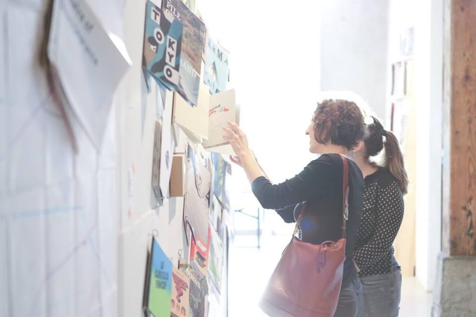 Two girls looking at publications which are hanging at a wall