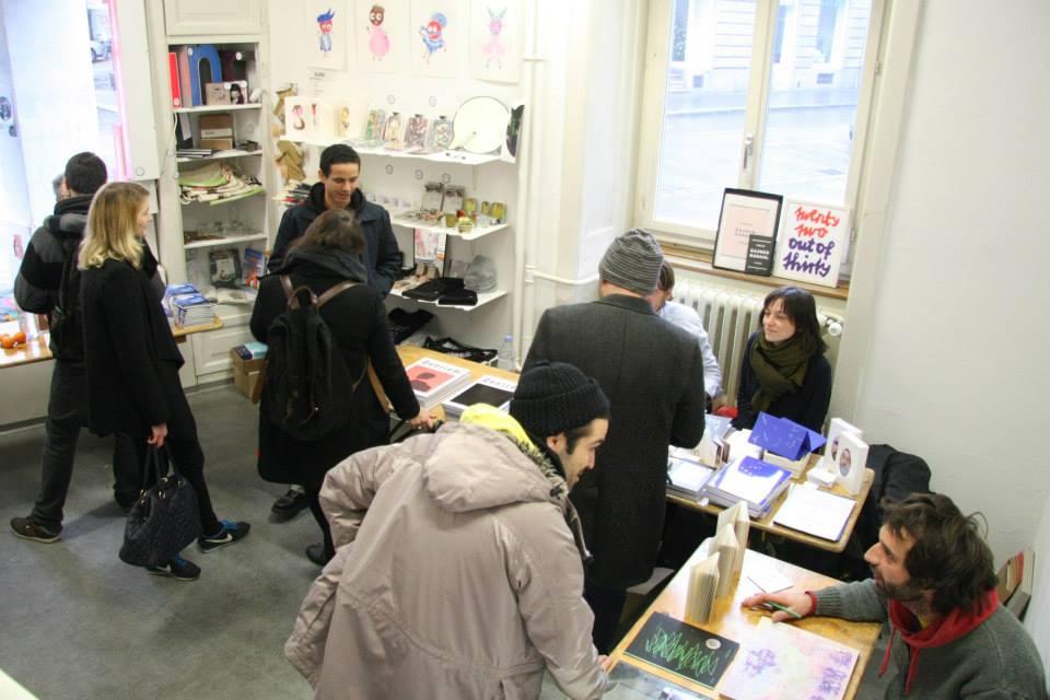 A room with book stands, shelves and people wandering around